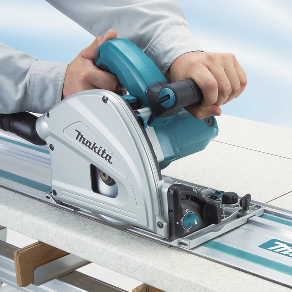 Scie plongeante Makita SP6000J guidée par son rail en aluminium pendant la coupe d’un panneau clair